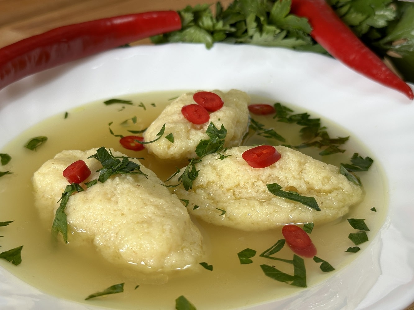 Semolina dumpling soup served with parsley and chili peppers